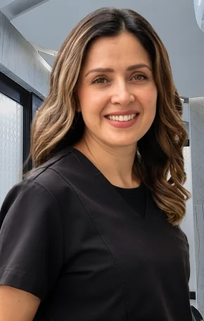 Dr. Dulce, an implantology specialist, smiling with arms crossed in professional black scrubs at Smile Makeover clinic