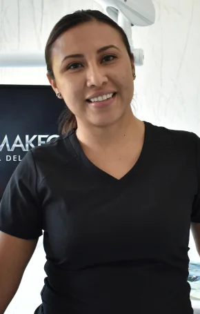 Dr. Martha, a restorative dentistry specialist, smiling in professional blue scrubs within a modern dental clinic setting.